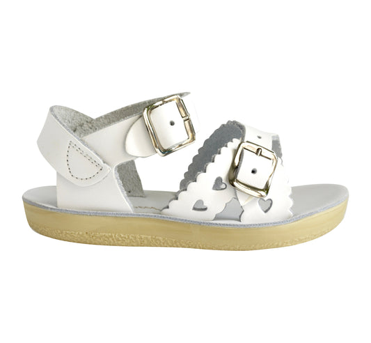A girls sandal by Salt Water Sandal in white with double buckle fastening across the instep and around the ankle. Featuring scallop edge and punched out heart detail. Right Sideview.