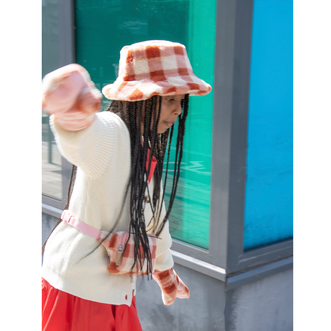 A bucket hat by Rockahula, style Furry Checked, in coral checked fur. Lifestyle image.