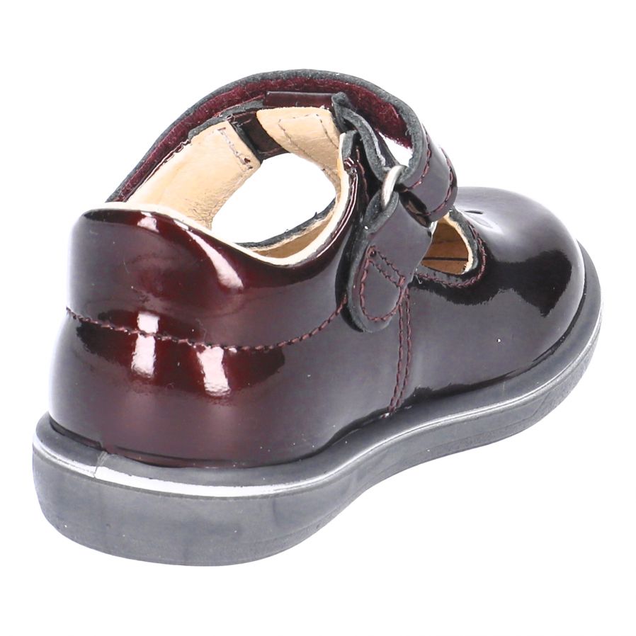 A girls T Bar shoe by Ricosta, style Winona, in Bordo patent with velcro fastening. Angled view.