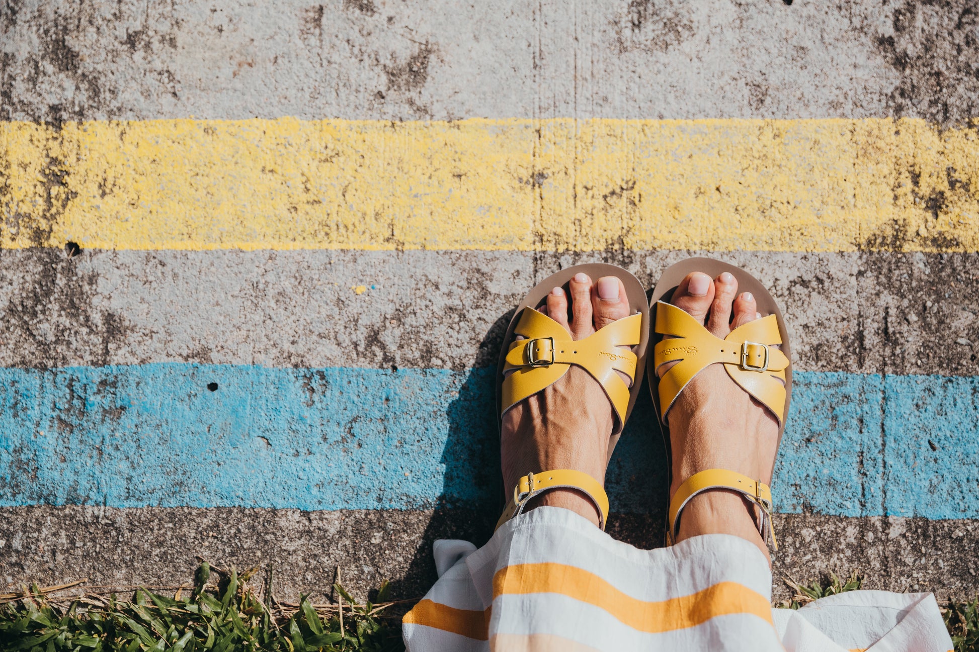 A Boardwalk style girls sandal by Salt Water Sandals in mustard with double buckle fastening across the toes and around the ankle. Open Toe and Sling-back. Looking down view.