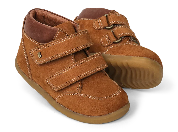 A pair of boys ankle boots by Bobux, style Step Up Timber, in tan nubuck with brown leather trim and double velcro fastening. Angled view.