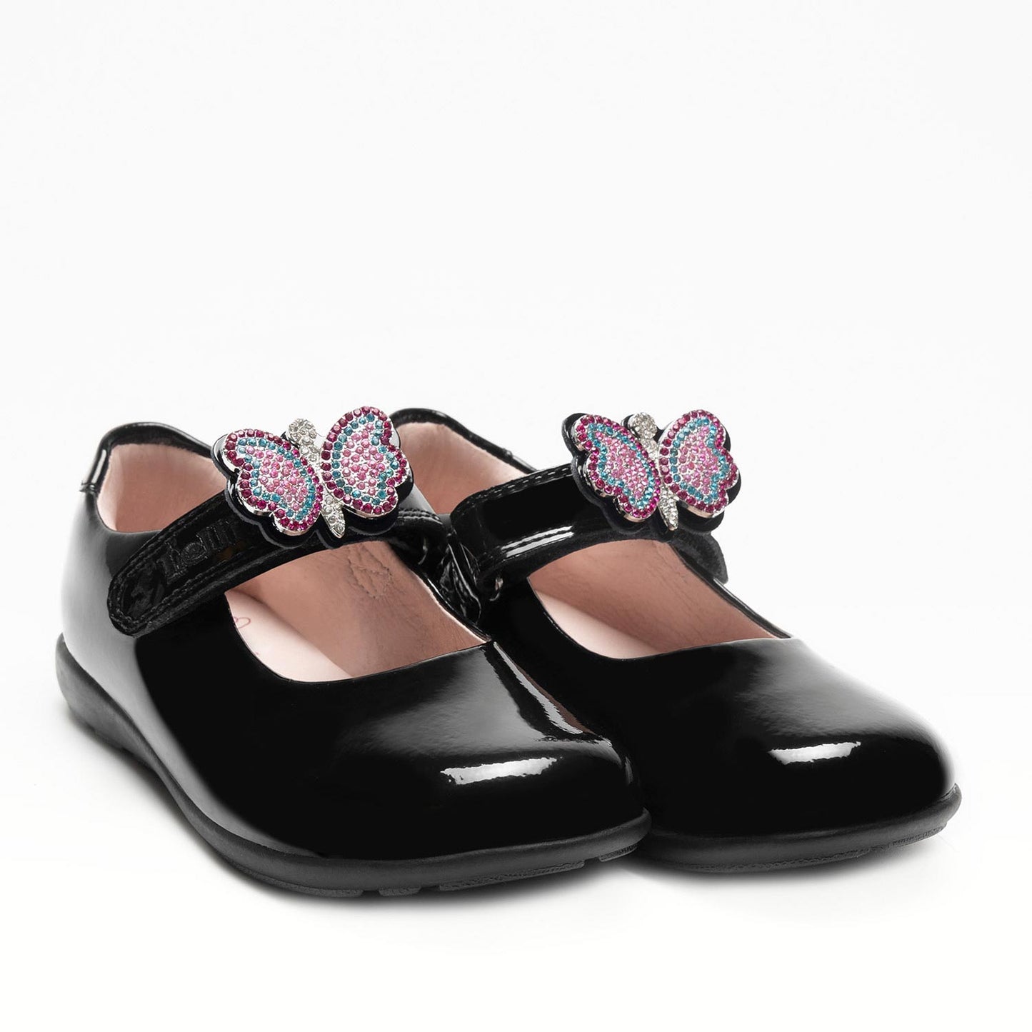 A girls Mary Jane school shoe by Lelli Kelly, style LKSO8641 Luna, in black patent leather with velcro fastening and detachable multicoloured embellished butterfly. Angled right side view of a pair.