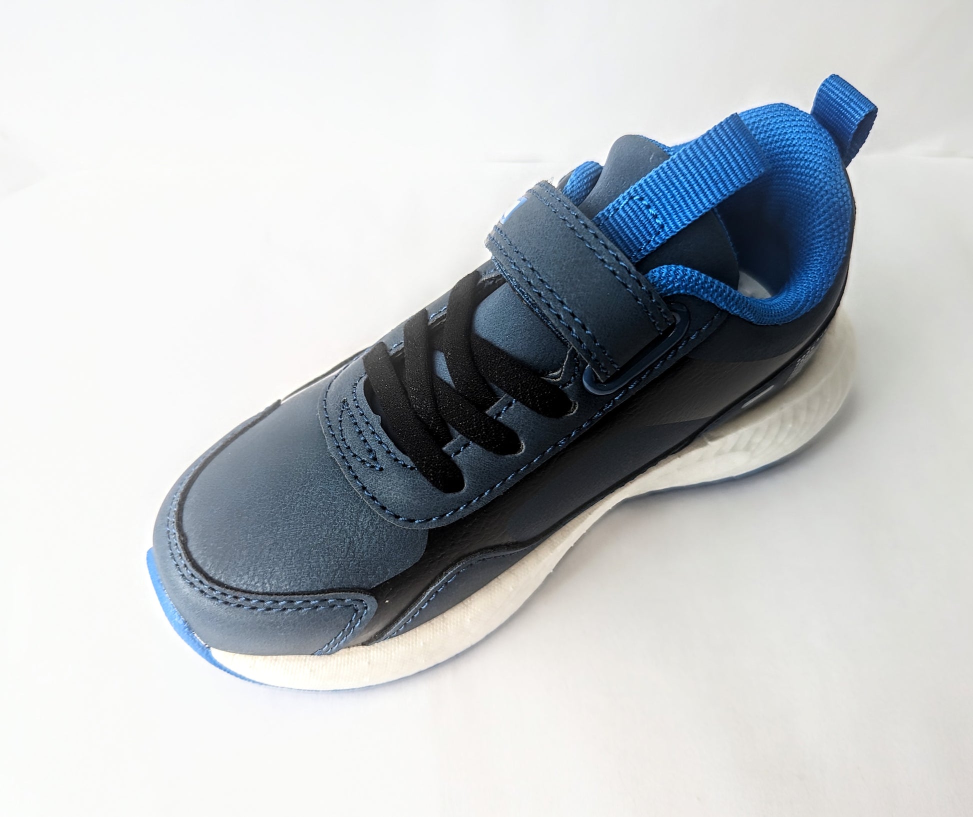 A boys trainer by Primigi, style B&G Rapid 4962511, in navy and blue with elastic lace and velcro fastening. Angled view from above.
