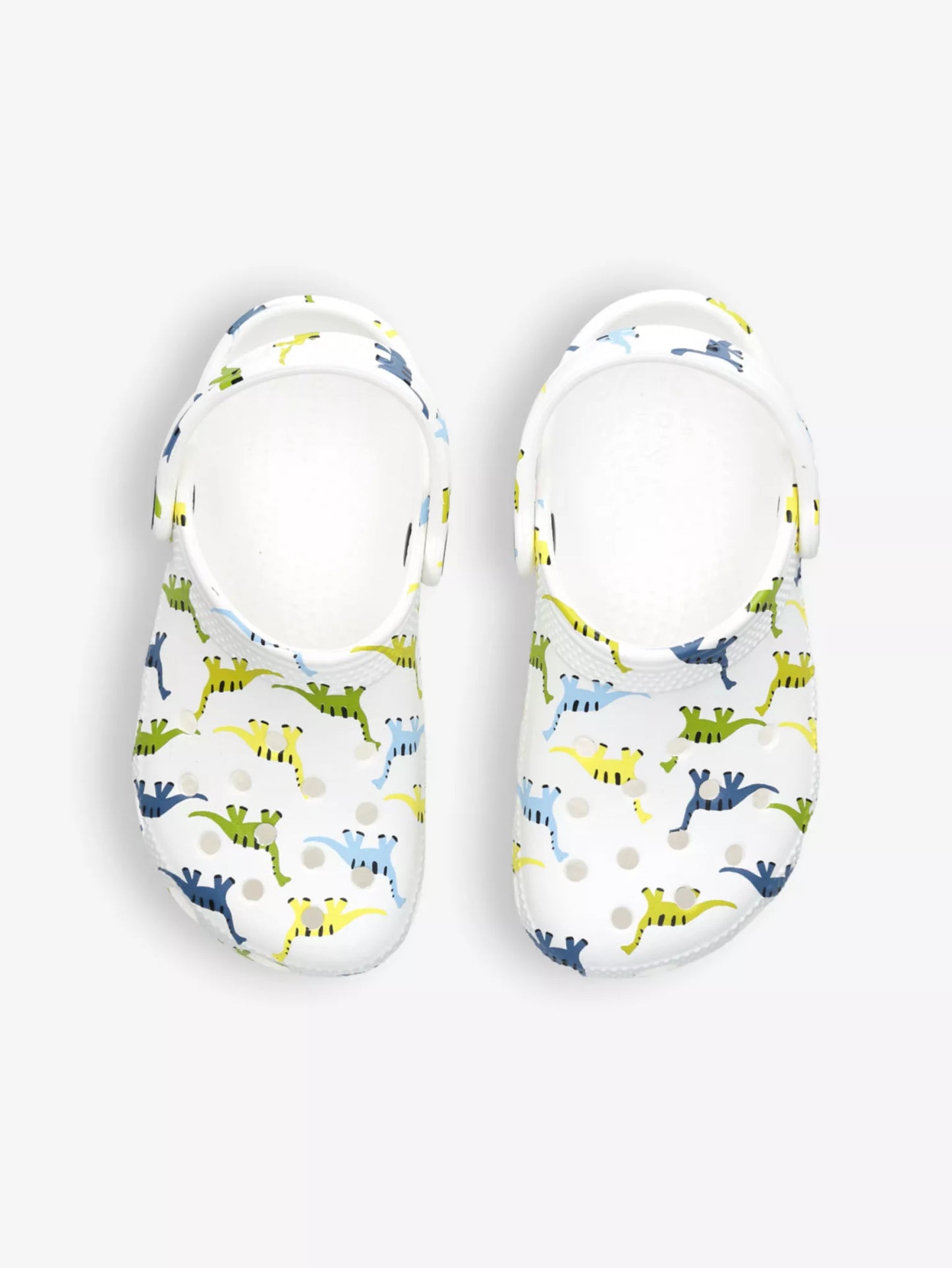 A classic clog by Crocs, style Tod in white with dinosaur print. Above view of a pair.