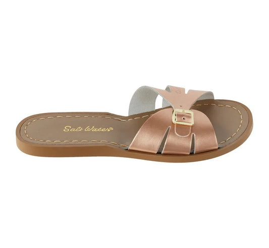 A Slide sandal by Salt Water Sandals in rose gold with single buckle fastening across the instep. Open toe and open back. Right side view.
