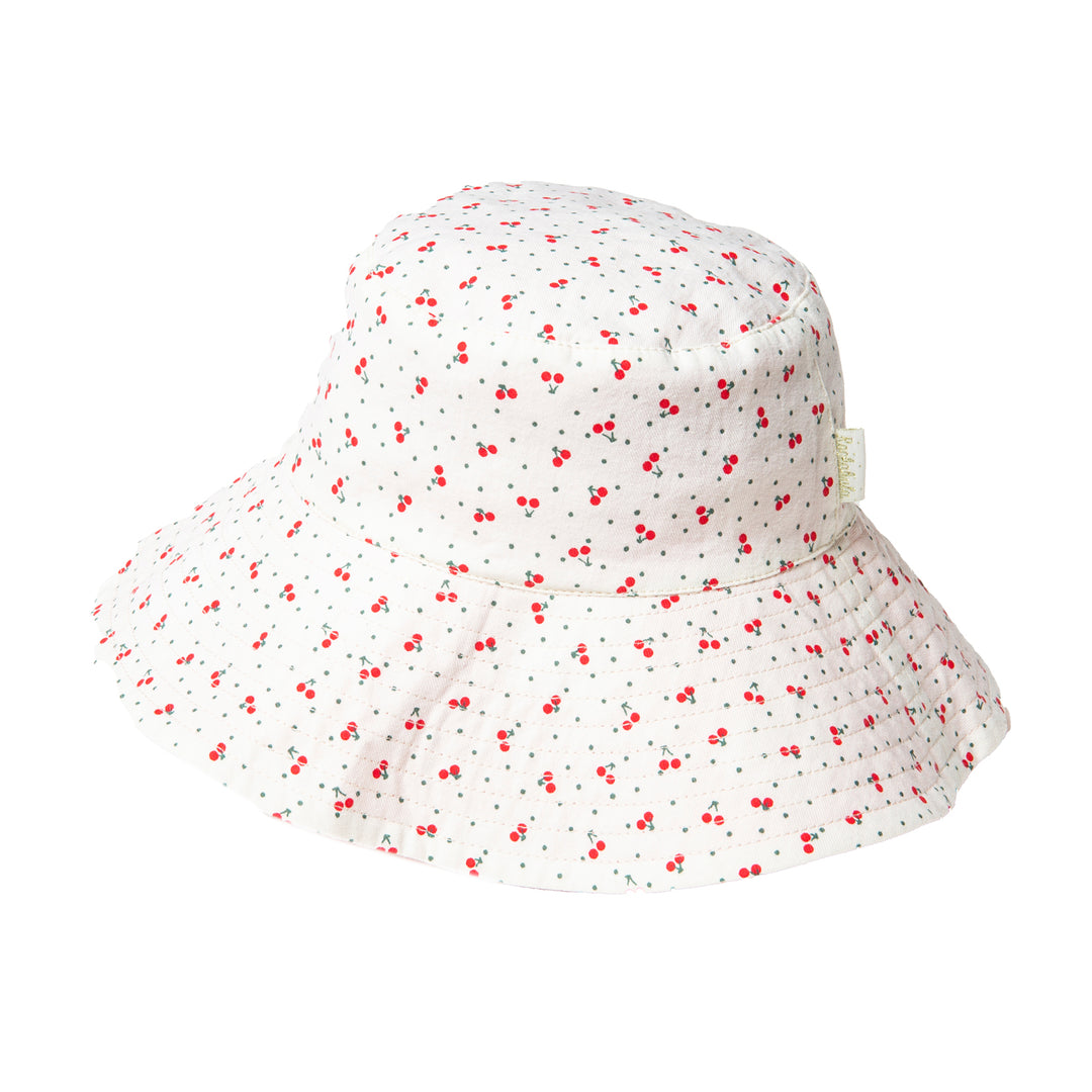 A reversible girls bucket hat by Rockahula, style Sweet Cherry, one side is white with red cherry print,the other red and white check. Front view.