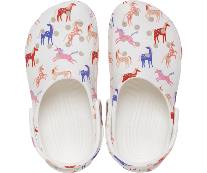 A classic clog by Crocs, style Tod in white with unicorn print. Above view of a pair.