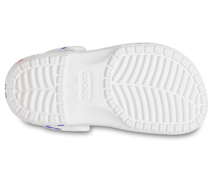 A classic clog by Crocs, style Tod in white with unicorn print. View of right sole.