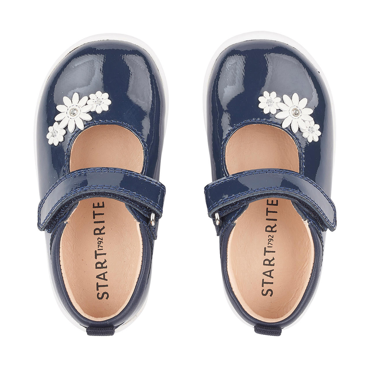 A pair of girls Mary Jane shoes by Start-Rite, style Fairy Tale, in navy patent leather on white sole unit with white flower and diamante detail. Velcro fastening. View from above.