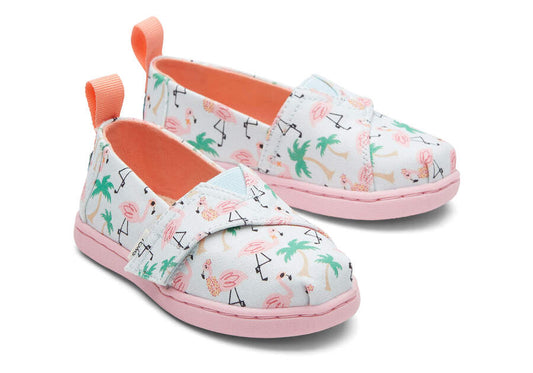 A girls canvas shoe by TOMS, style Alpargata Flamingo, in soft blue flamingo print with velcro fastening. Front view of a pair.