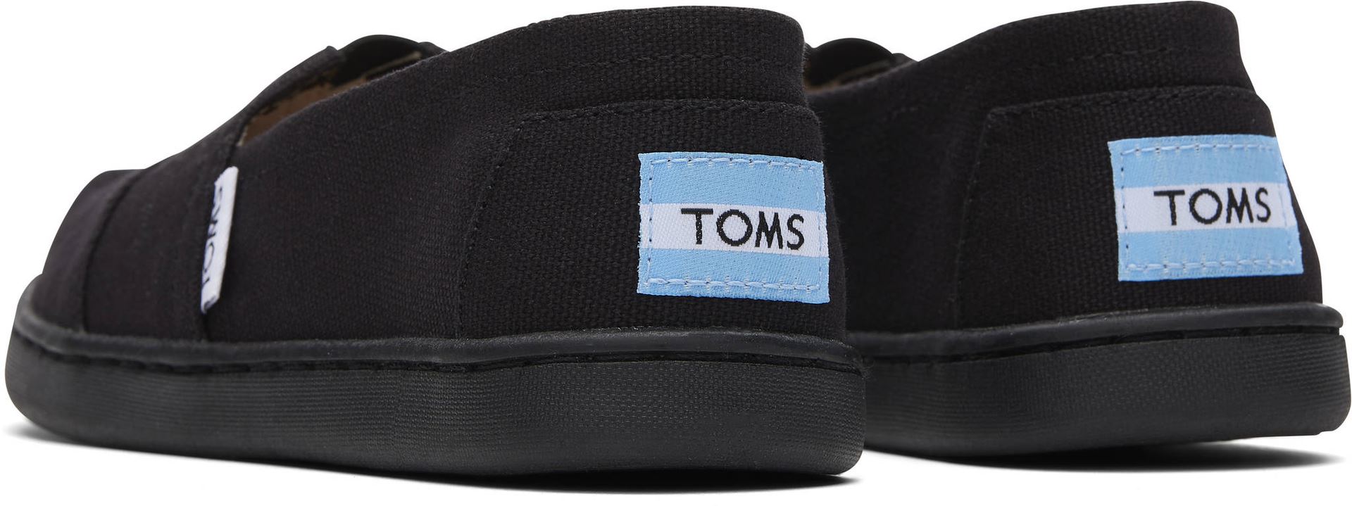 A unisex canvas shoe by TOMS, style Alpargata, a slip on in black. Back view of a pair.