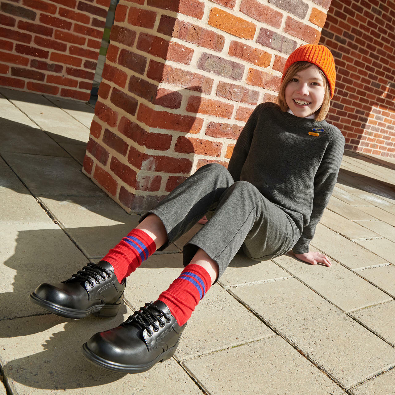 A boy wearing a pair of boys school shoes by Start Rite,style Isaac, in black leather with lace up fastening. Angled view.