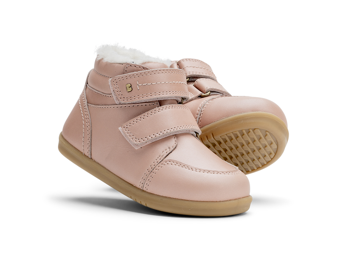 A pair of girls waterproof fur lined ankle boots by Bobux,style Timber, in pale pink with double velcro fastening. Angled  view.