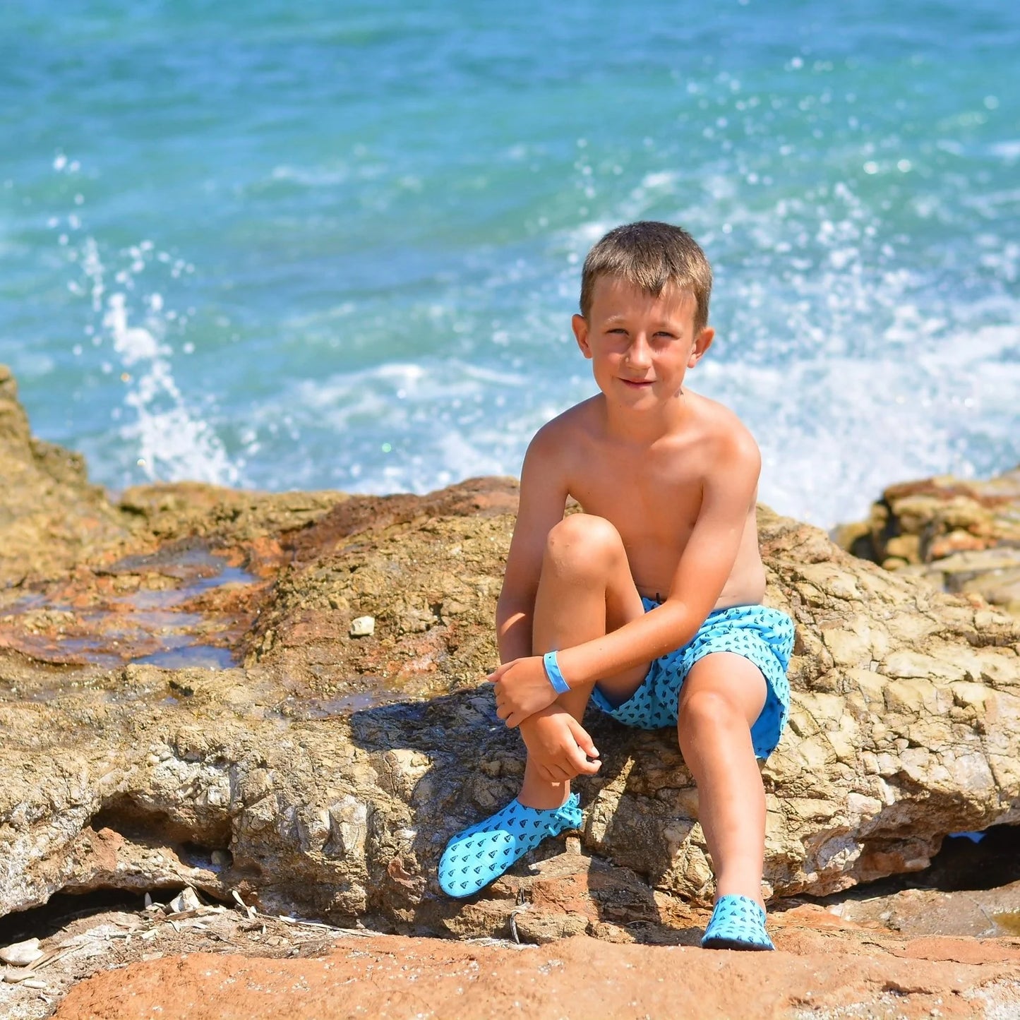 A boy wearing swim shorts by Slipfree, style Peter, in teal. Front view.